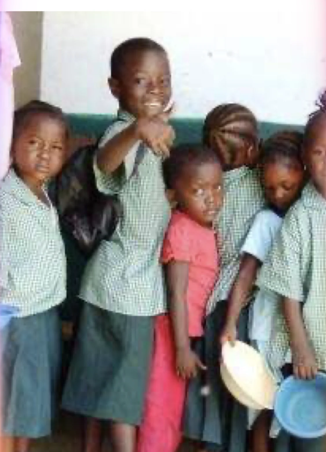 Young students holding bowls for a school meal.